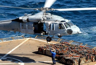 A Sailor assigned to the Military Sealift Command ammunition ship USNS Flint (T-AE 32) attaches a sling to an MH-60S Seahawk helicopter, assigned the "Blackjacks" of Helicopter Sea Combat Squadron (HSC) 21, during an ammunition on load with the Nimitz-class nuclear-powered aircraft carrier USS Ronald Reagan (CVN 76). Ronald Reagan is underway in the Pacific Ocean conducting routine carrier operations.